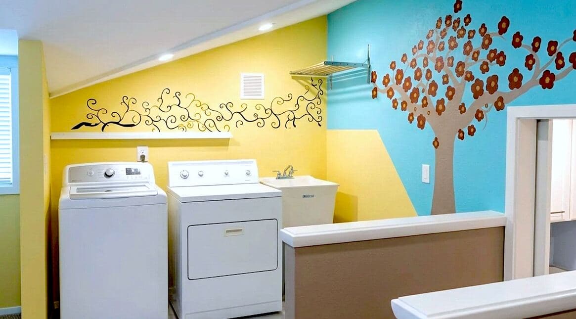 Finished laundry room with colorful painted walls, washer, dryer, shelving, and utility sink