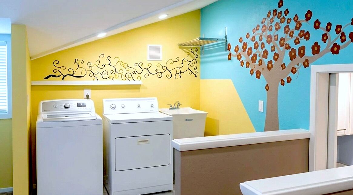 Finished laundry room with colorful painted walls, washer, dryer, shelving, and utility sink