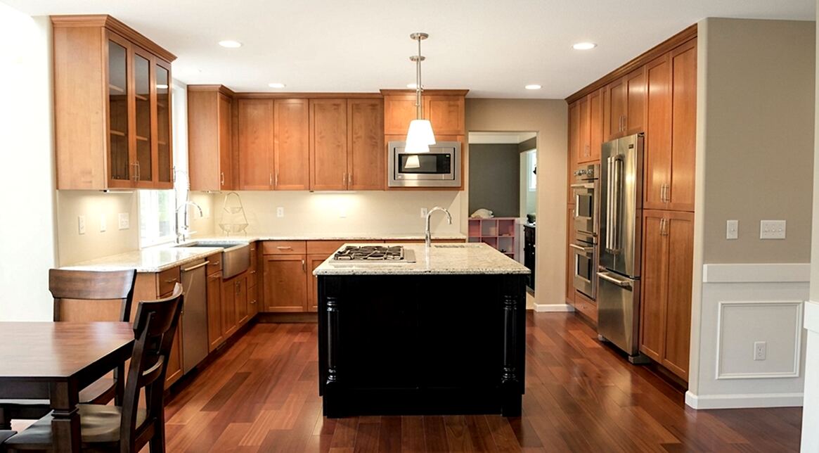 Remodeled kitchen with wood cabinets, dark island, farmhouse sink, and built-in appliances