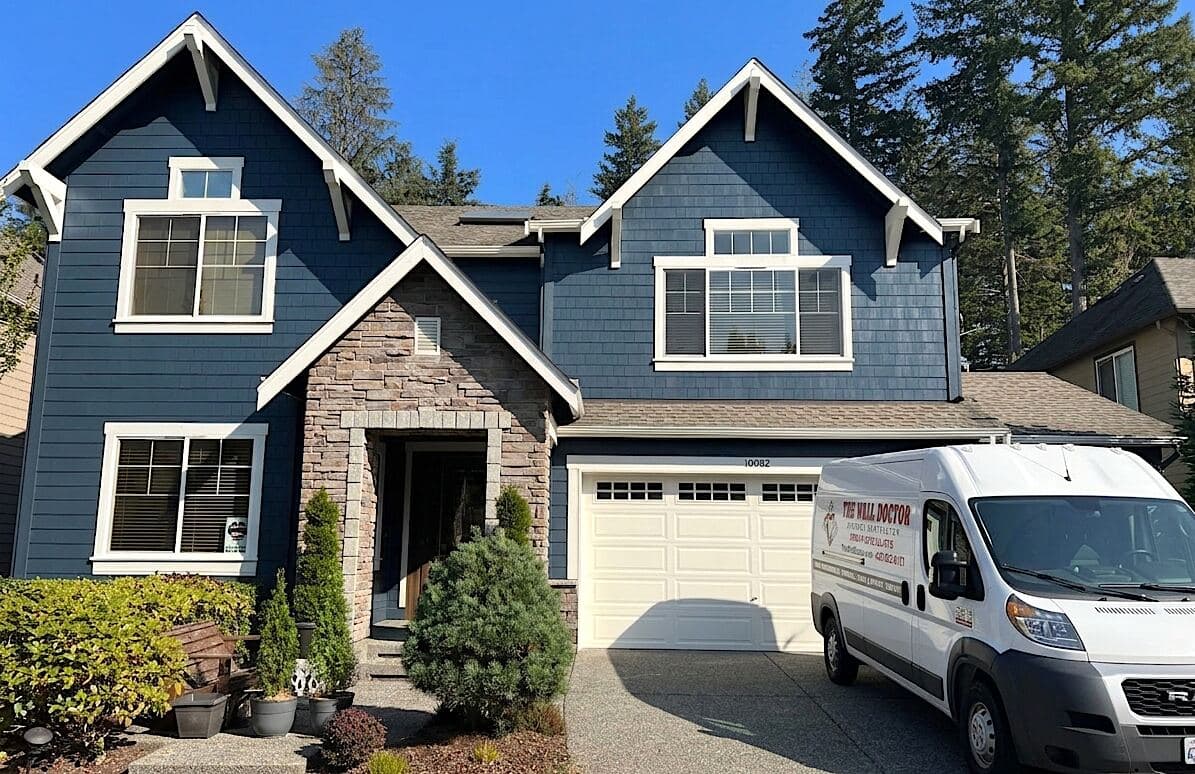 Blue Bellevue home exterior painted by The Wall Doctor with white trim and company van